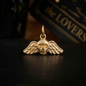 Bronze Flying Skull Charm on dark background