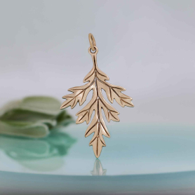 Bronze Mugwort Leaf Charm on blue background
