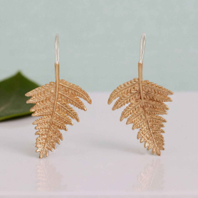 Bronze fern earrings on blue background
