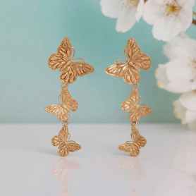 Bronze triple butterfly ring on pink background