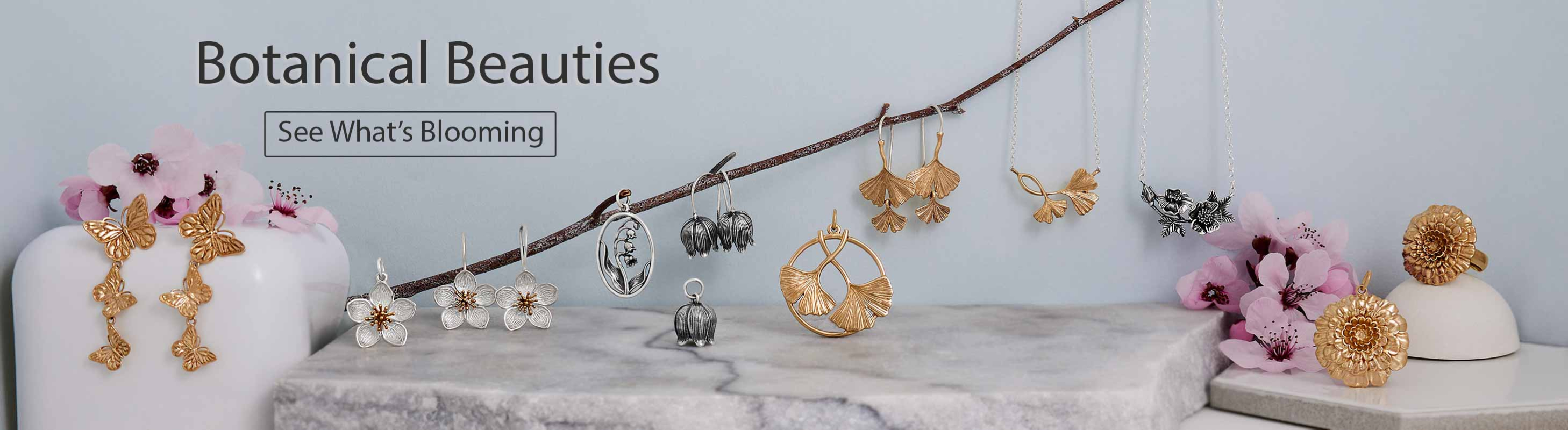 Flower charms, earrings and rings on a blue background with cherry blossom flowers