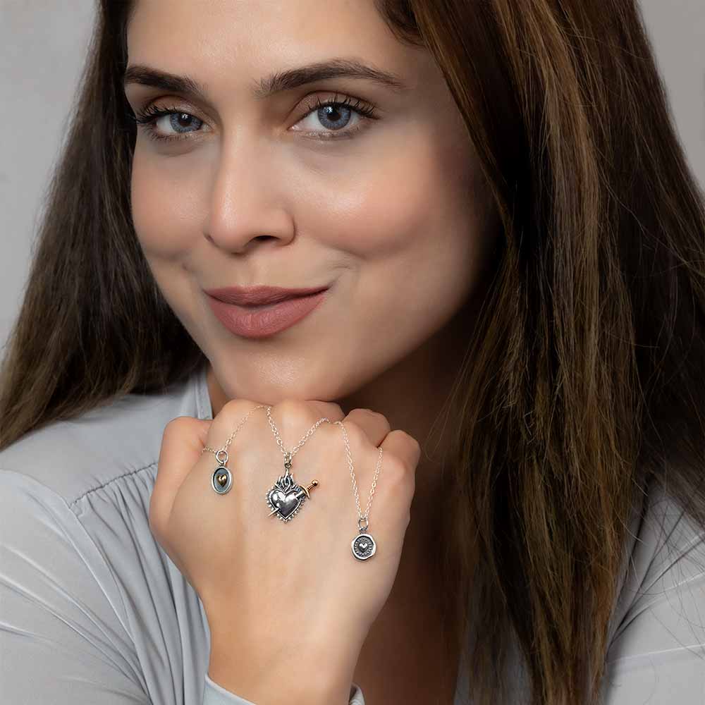 Women holding silver heart necklaces