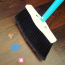 SweepEasy&reg; Broom being used to sweep and scrape in a kitchen setting, showcasing its dual-function design.