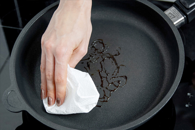 A hand with cloth showing the simply cleaning process for the AMT pans